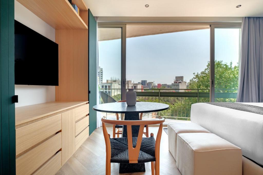 a bedroom with a table and a bed and a balcony at Casa Cibeles by Lumina in Mexico City