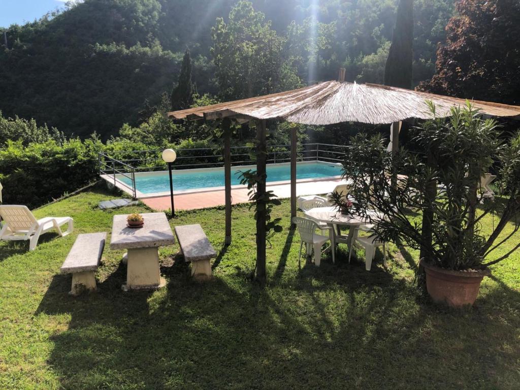 ein Picknicktisch und ein Sonnenschirm neben einem Pool in der Unterkunft La vecchia canonica in Fivizzano