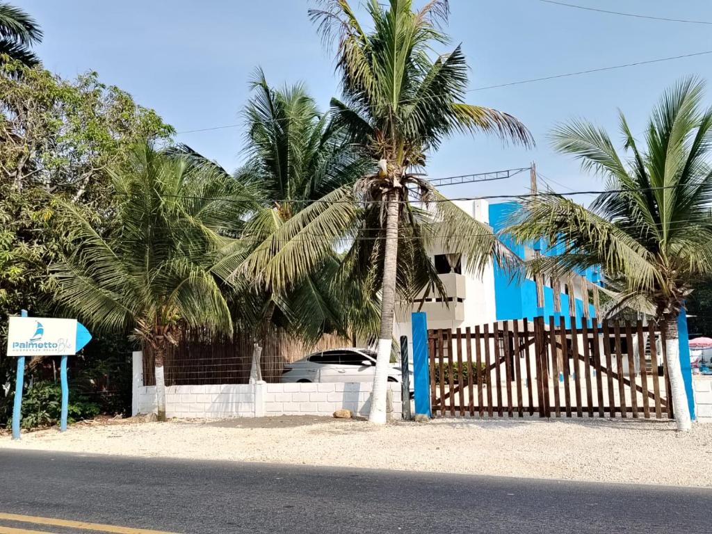 une clôture avec des palmiers devant une maison dans l'établissement Hotel Palmetto Beach Coveñas, à Coveñas
