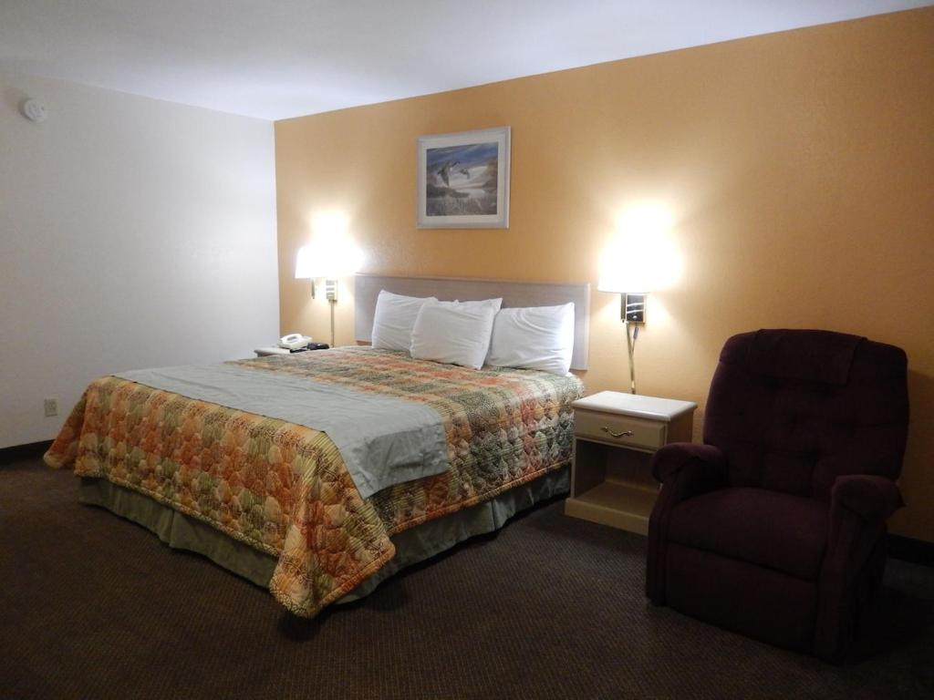a hotel room with a bed and a chair at Pearsall Executive Inn in Pearsall