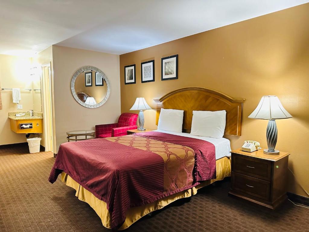 Habitación de hotel con cama y espejo en Franciscan Inn Motel en Vista