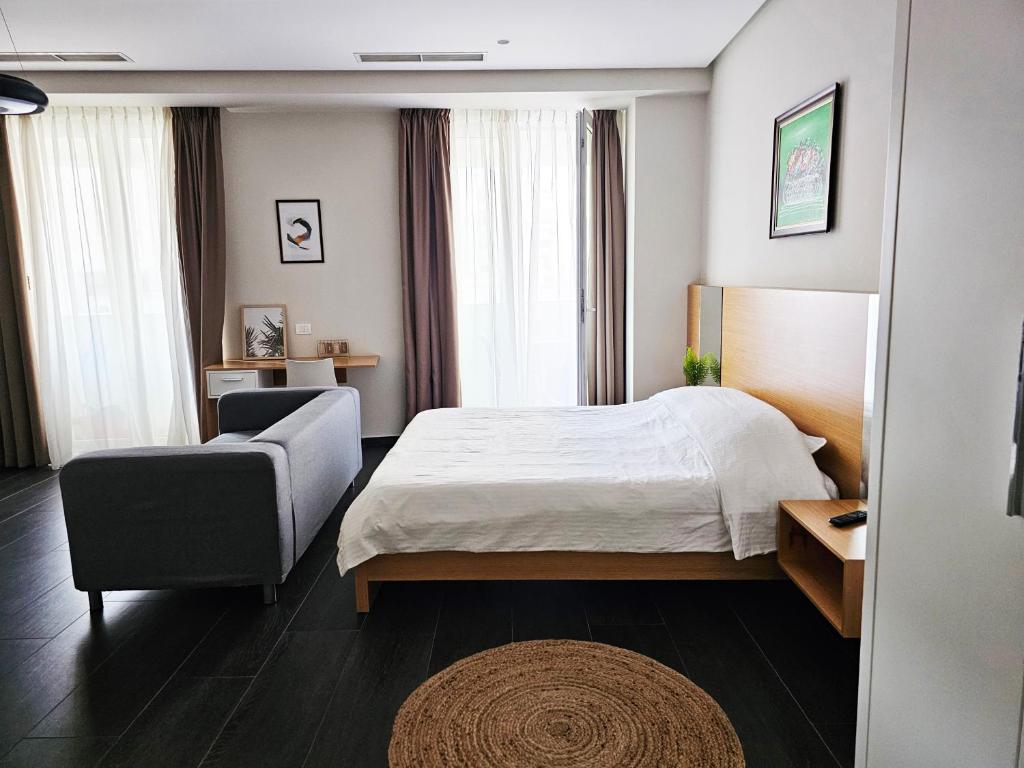 ティラナにあるMagnet Residence Condo 2 self check inのベッドと椅子のあるホテルの部屋