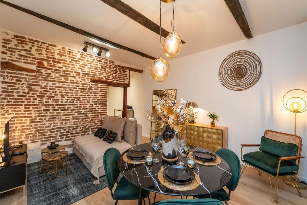 a living room with a table and a brick wall at Appartement typique hyper centre Albi - Neuf Premium - Parking gratuit in Albi