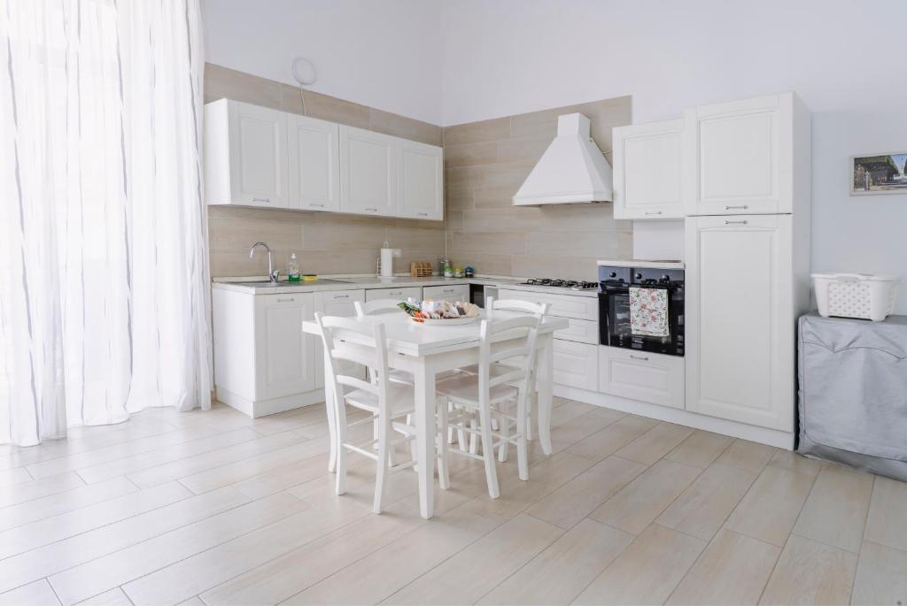 una cucina con armadi bianchi e tavolo e sedie bianchi di Gli Appartamenti della Villa a Santa Maria Capua Vetere