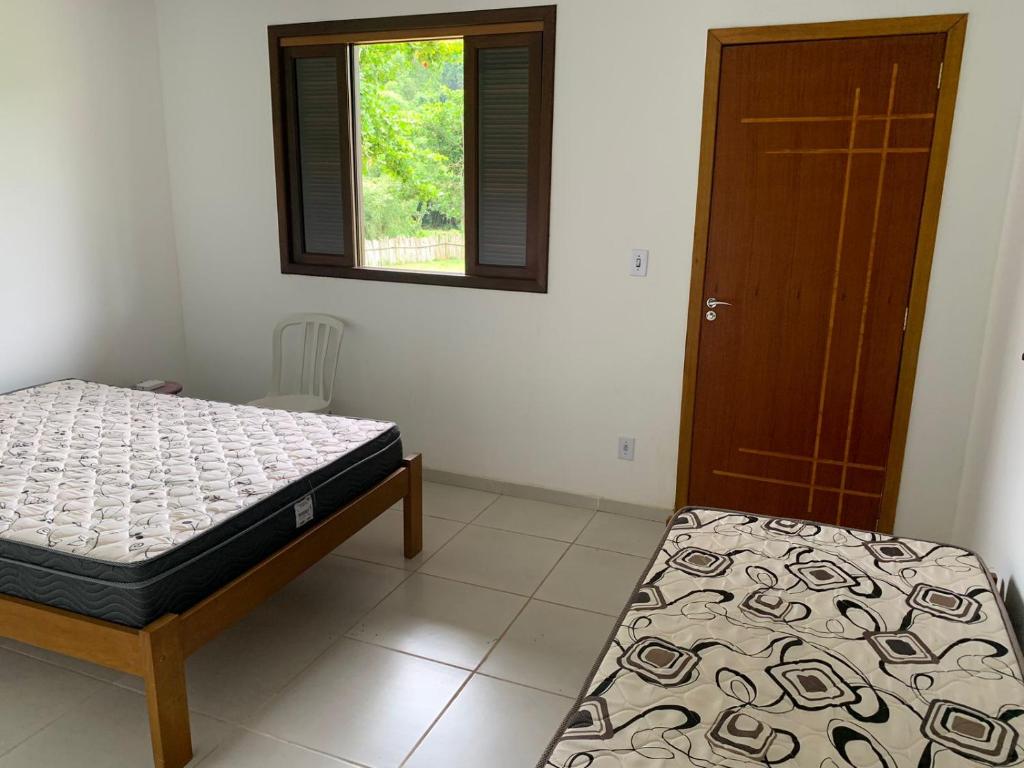 1 dormitorio con 2 camas, ventana y puerta en Fazenda Cachoeira - Rialto, en Barra Mansa