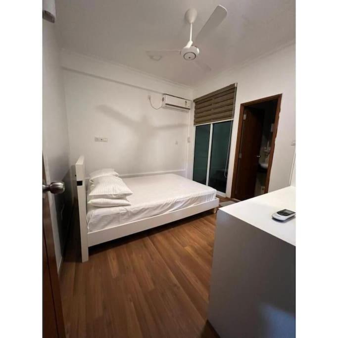 una camera da letto con un letto con lenzuola bianche e un pavimento in legno di Ocean Apartments Hulhumale (Lot 10819) a Città di Malé