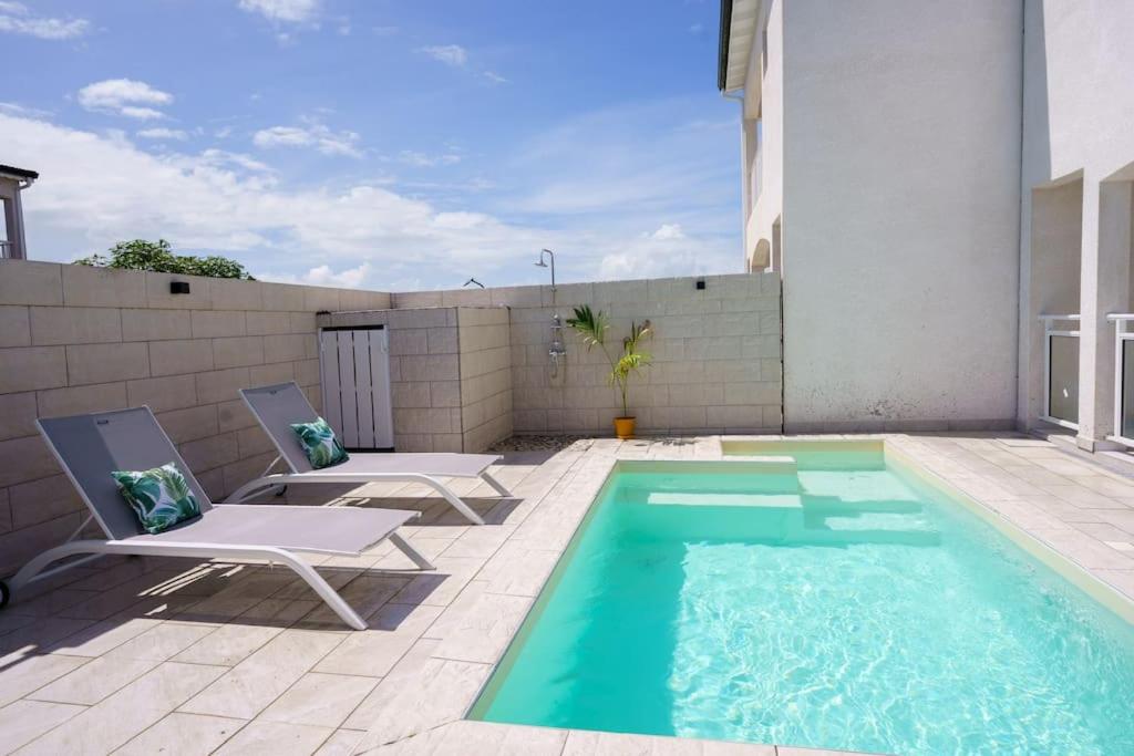 - une piscine avec 2 chaises longues à côté d'une maison dans l'établissement Villa des Ixoras, à Baie-Mahault