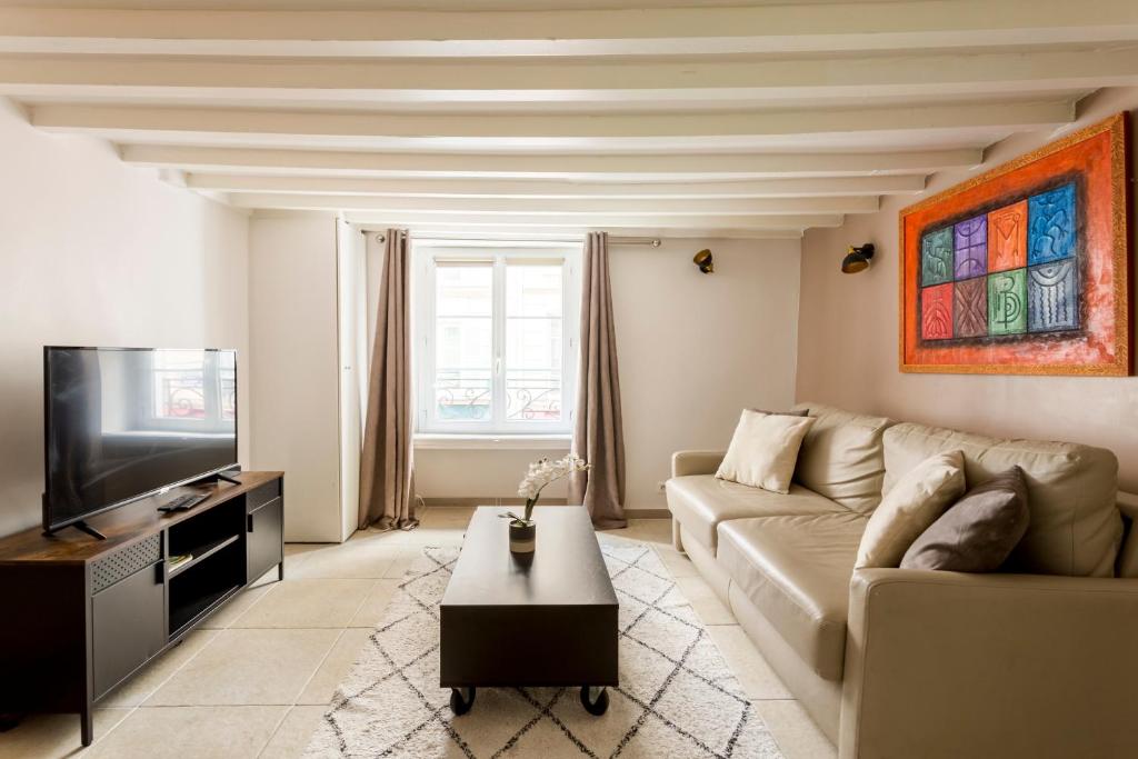 een woonkamer met een bank en een tv bij Rivoli Vieille du temple in Parijs