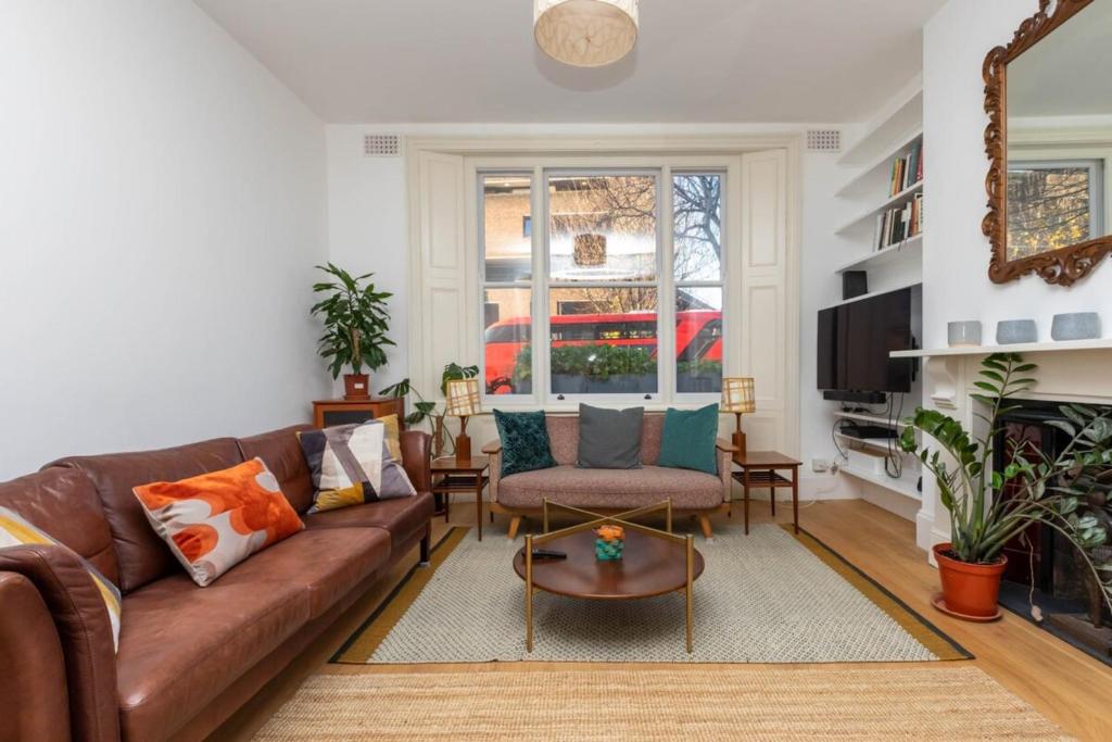 a living room with a brown couch and a fireplace at Spacious 2BD Flat By Regents Park & Camden Town! in London