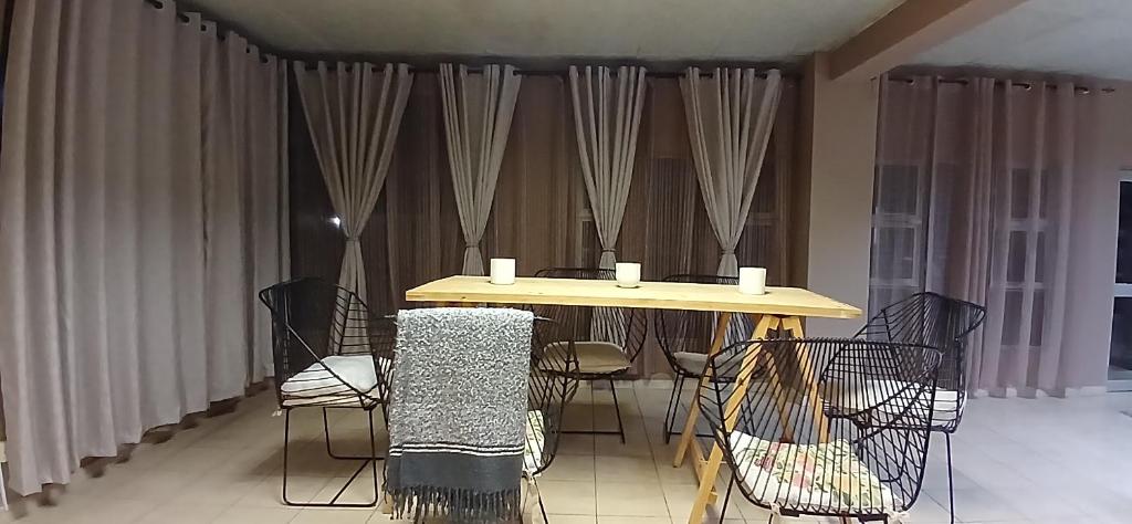 een tafel en stoelen in een kamer met gordijnen bij Bakaya Hotel Tlokweng in Gaborone