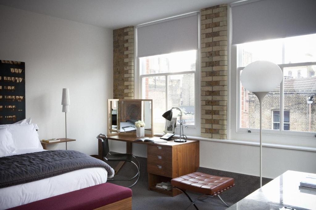 a bedroom with a bed and a desk and a window at Boundary Shoreditch in London