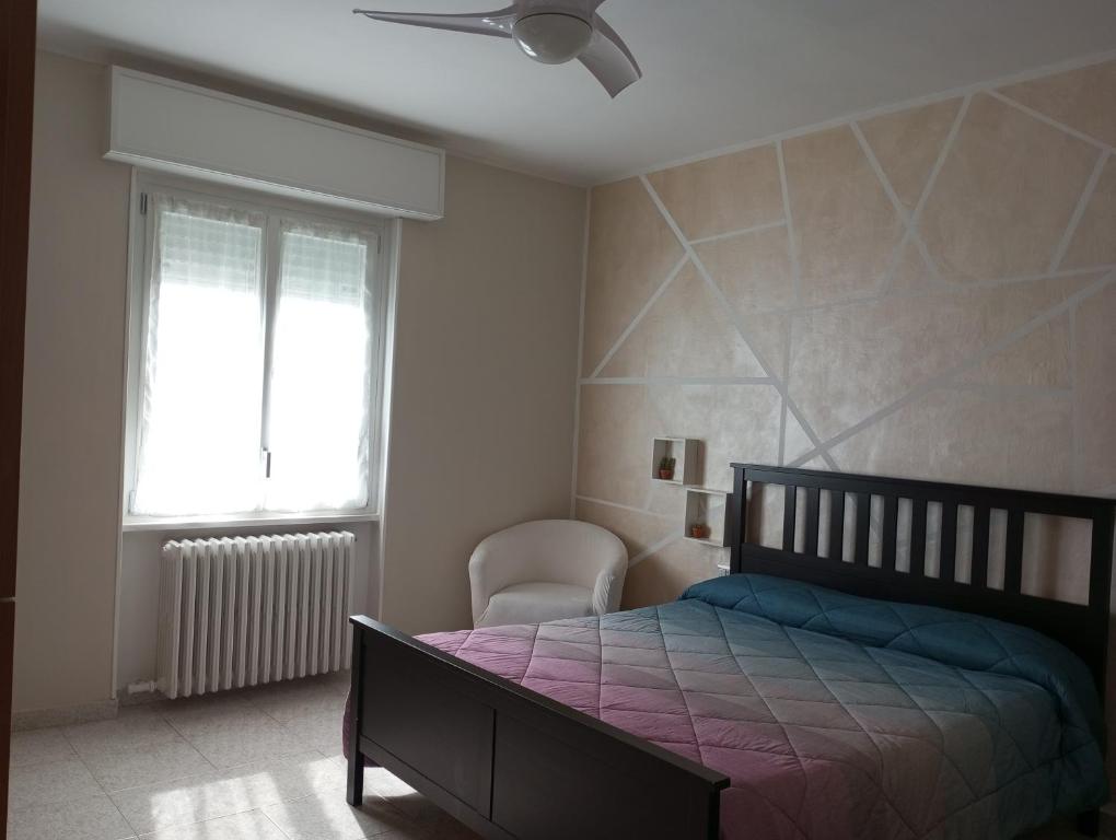 ein Schlafzimmer mit einem Bett, einem Fenster und einem Stuhl in der Unterkunft Casa vacanze il fiore di loto in Zibido San Giacomo