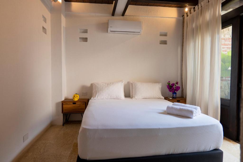 a bedroom with a large white bed and a window at Casa Familiar - Maria de las Palmas -Getsemani in Cartagena de Indias