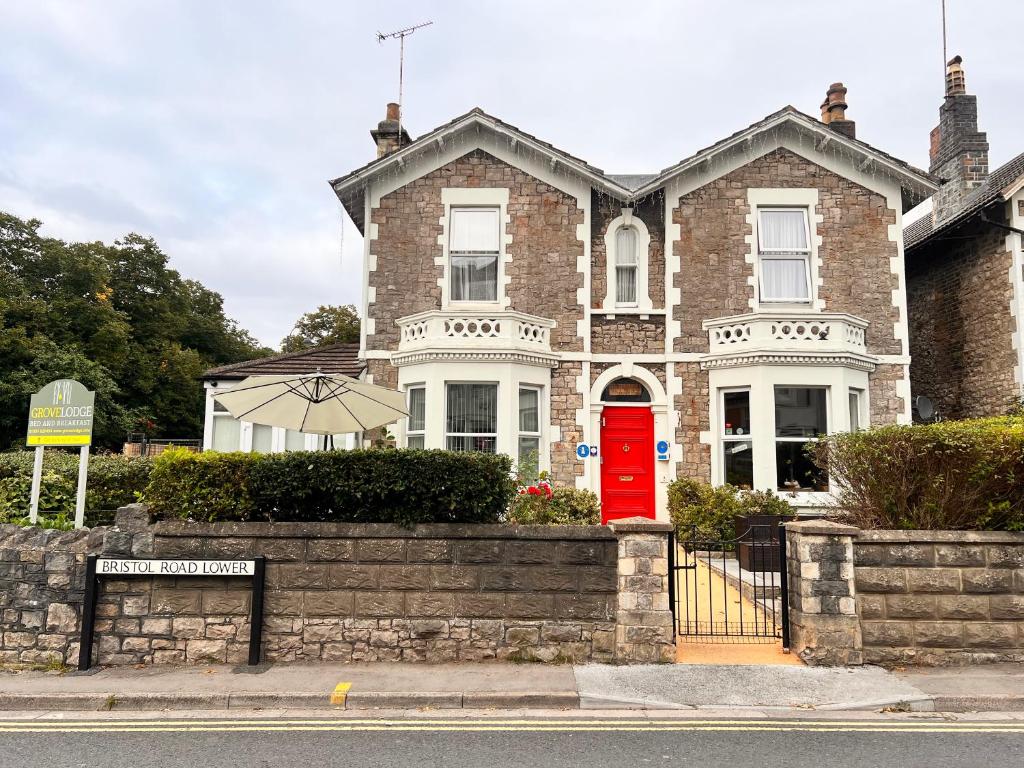 uma casa de tijolos com uma porta vermelha numa rua em The Grove em Weston-super-Mare