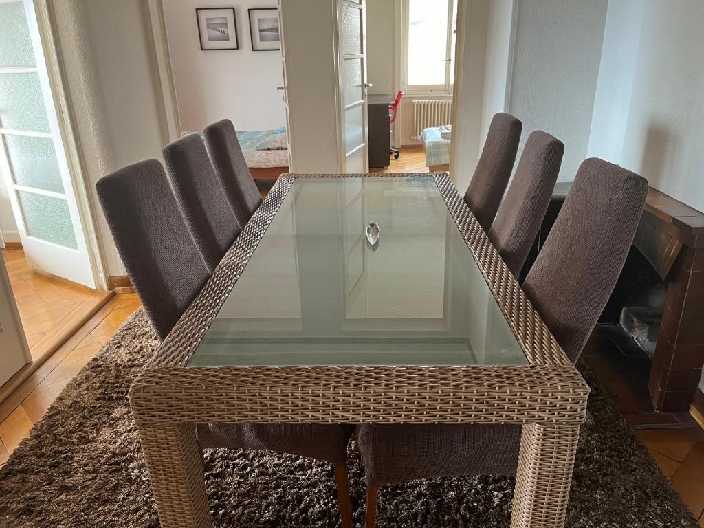 une table à manger en verre avec des chaises autour de celle-ci dans l'établissement Grand Appartement avec 3 chambres à coucher, à Lausanne