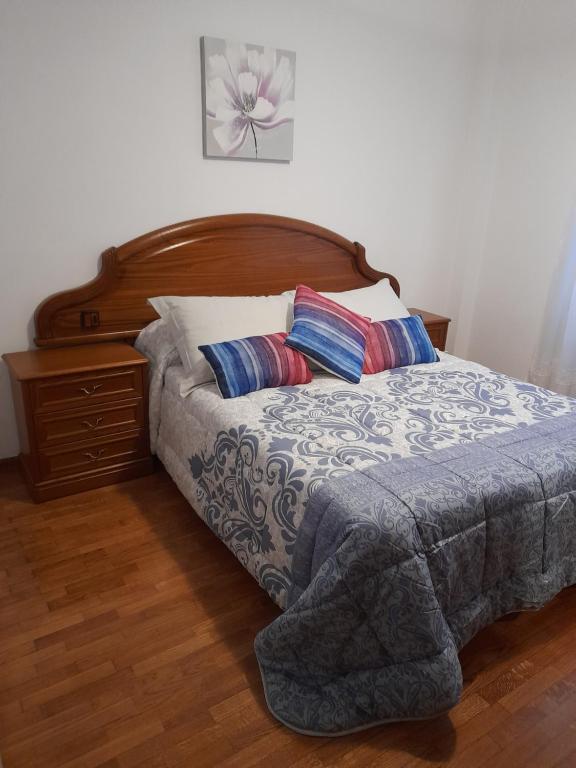 uma cama com uma cabeceira em madeira e 2 almofadas em Carmina fondon 3 em Cangas de Onís