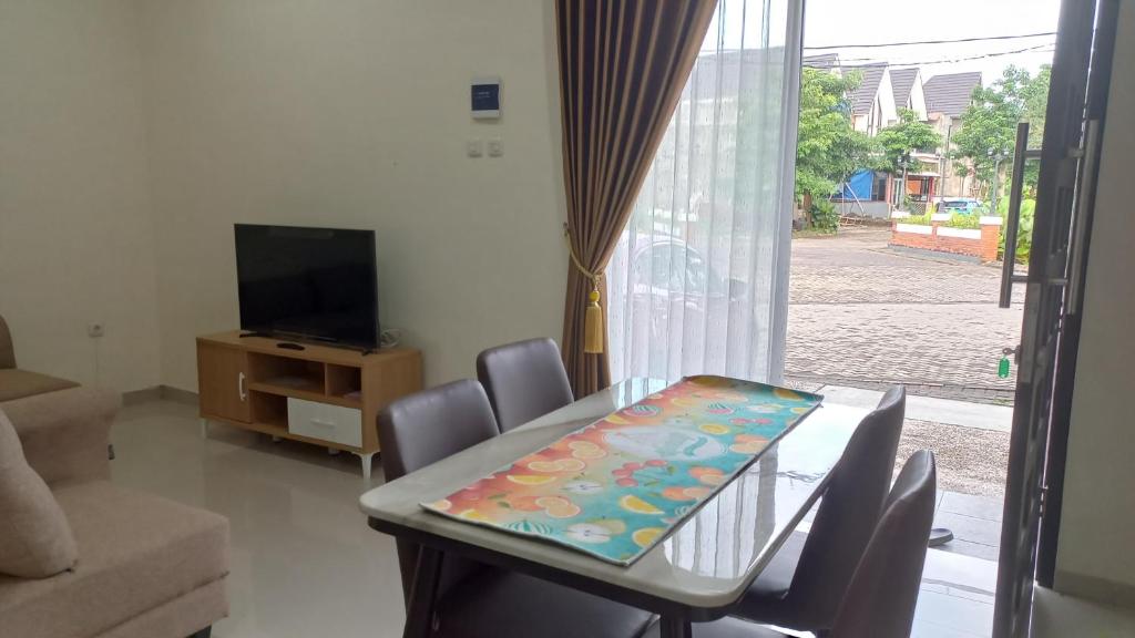ein Esszimmer mit einem Tisch, Stühlen und einem TV in der Unterkunft MILLI Home - Family Home Stay in Blimbing