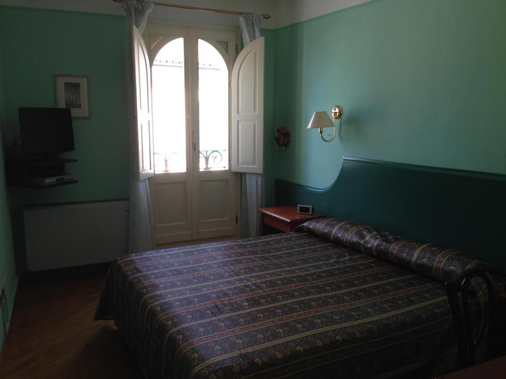 1 dormitorio con cama, ventana y puerta en Hotel San Genesio en Fabbrico