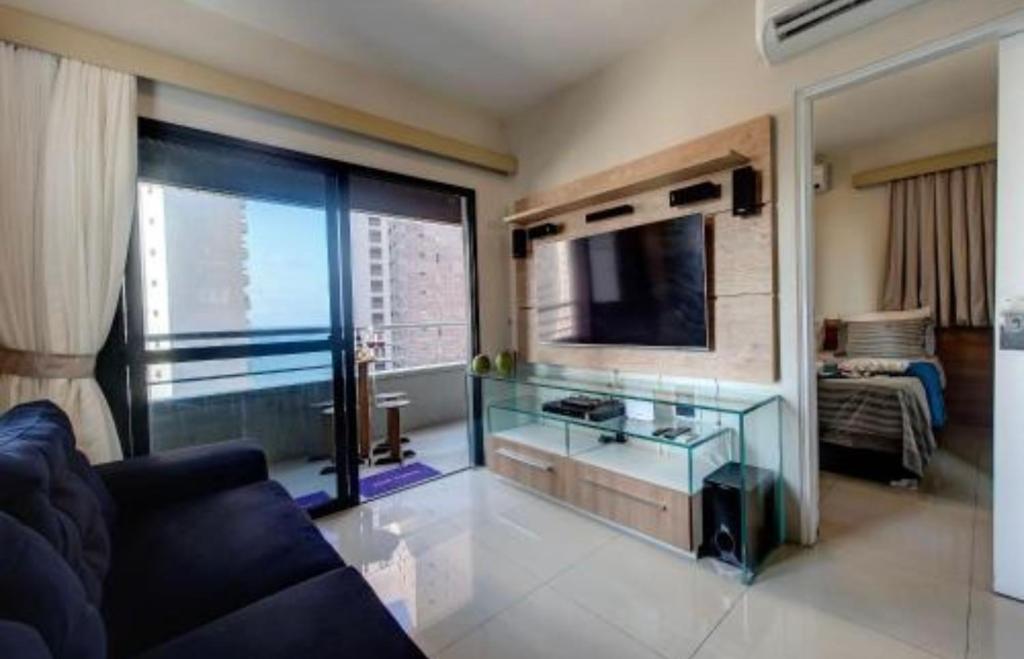 ein Wohnzimmer mit einem Sofa und einem Flachbild-TV in der Unterkunft Flat Mar Azul - Beira Mar Fortaleza in Fortaleza