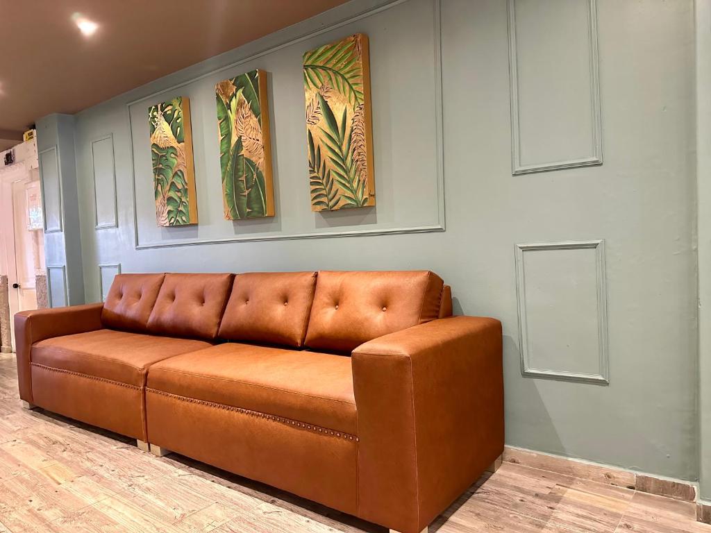 - un canapé brun dans une pièce avec trois peintures dans l'établissement Hotel Londres Real, à Valledupar