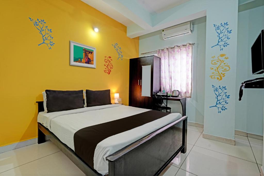 a bedroom with a large bed with yellow walls at OYO Flagship 81266 Slv Hotel in Bangalore