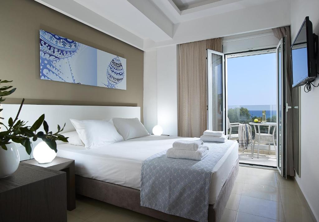 a bedroom with a white bed and a balcony at Coral Apartments in Ierapetra