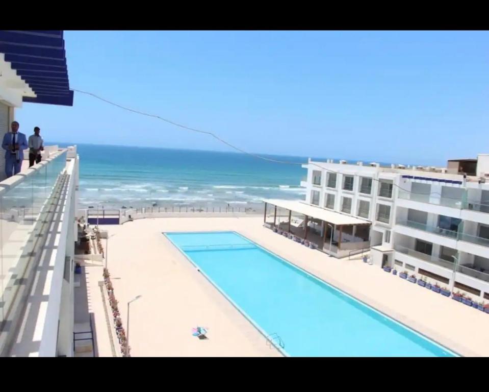 a swimming pool on top of a building next to the ocean at Appartement Plage près d’Agadir in Aourir