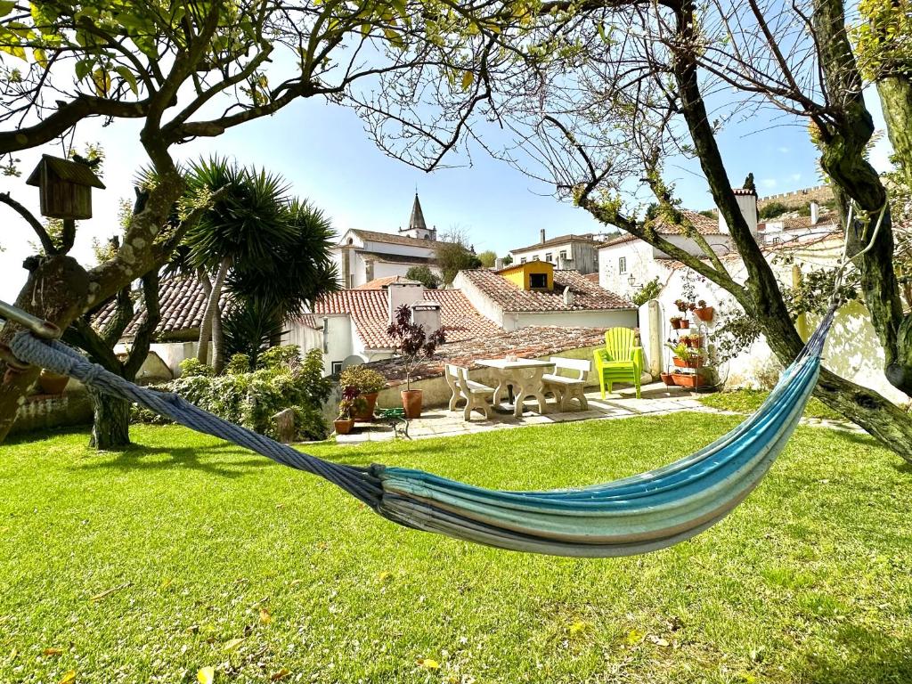 a blue hammock hanging from a tree in a yard at Casa do Candeeiro in Óbidos