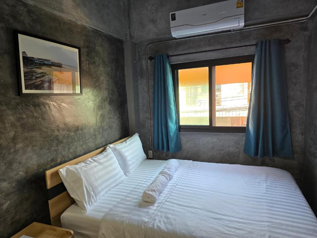 a bedroom with a white bed with a window at Captain Joe Cafe & Hostel in Hua Hin