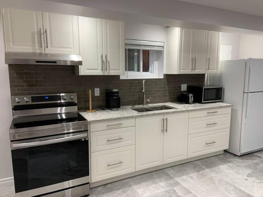 a kitchen with white cabinets and stainless steel appliances at Luxurious brand new ground level apartment in Mississauga