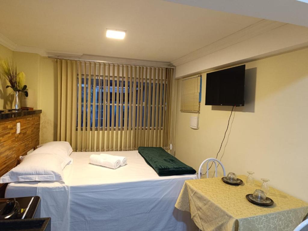 Habitación de hotel con cama y TV en Aconchego Vila Rica - Mariana, en Mariana