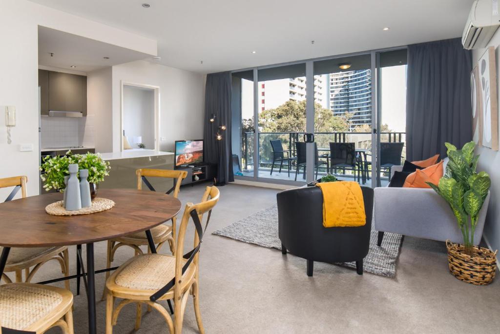 a living room with a table and chairs and a kitchen at Central 1-Bed with Parking BBQ and Indoor Pool in Canberra