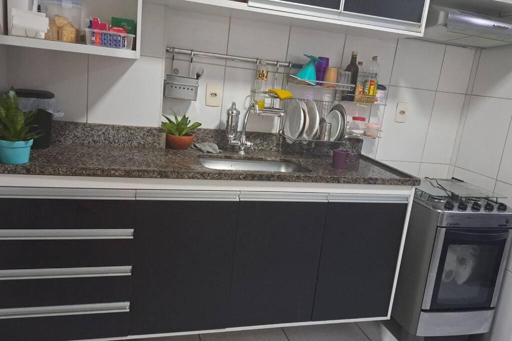 a kitchen counter with a sink and a stove at Apartamento na Ponta Negra, 2 quartos, sendo uma suite in Manaus