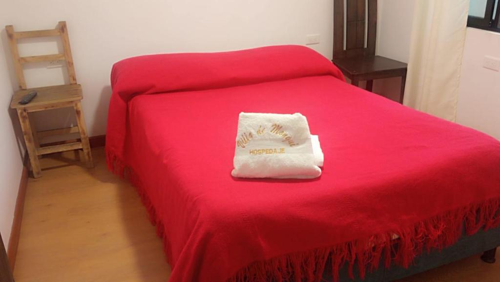 ein rotes Bett mit einem weißen Kissen darauf. in der Unterkunft Hotel Villa de Mongui in Monguí