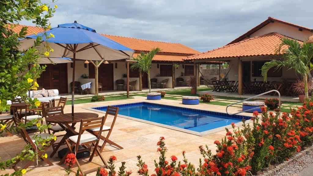 a pool with chairs and a table and an umbrella at Belladora Pousada in Barra Grande