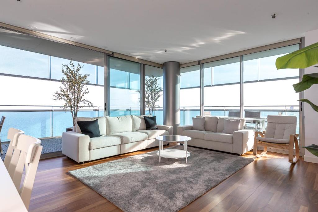 ein Wohnzimmer mit weißen Möbeln und großen Fenstern in der Unterkunft Luxury Apartment With Sea View! in Barcelona
