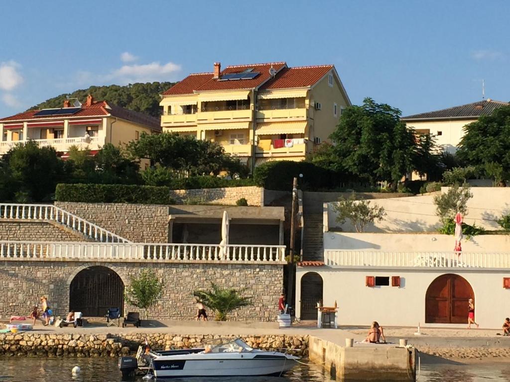 a boat in a body of water next to buildings at Apartments Kaja in Rab