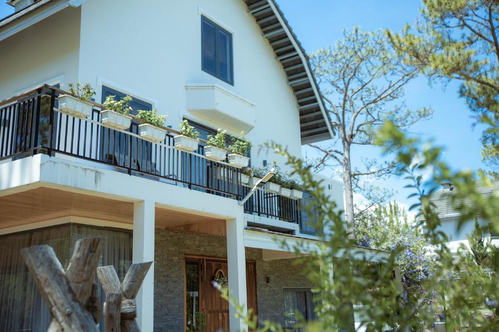 a white building with a balcony with plants on it at Kim Ngan Hills Resort Da Lat. in Da Thien