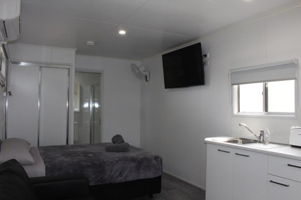 a small bedroom with a bed and a sink at Huntsville Caravan Park in Maryborough