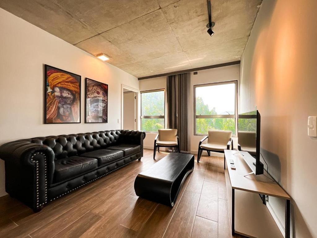 a living room with a black leather couch and chairs at PRAIA BRAVA AP Mobiliado Condominio COMPLETO in Itajaí