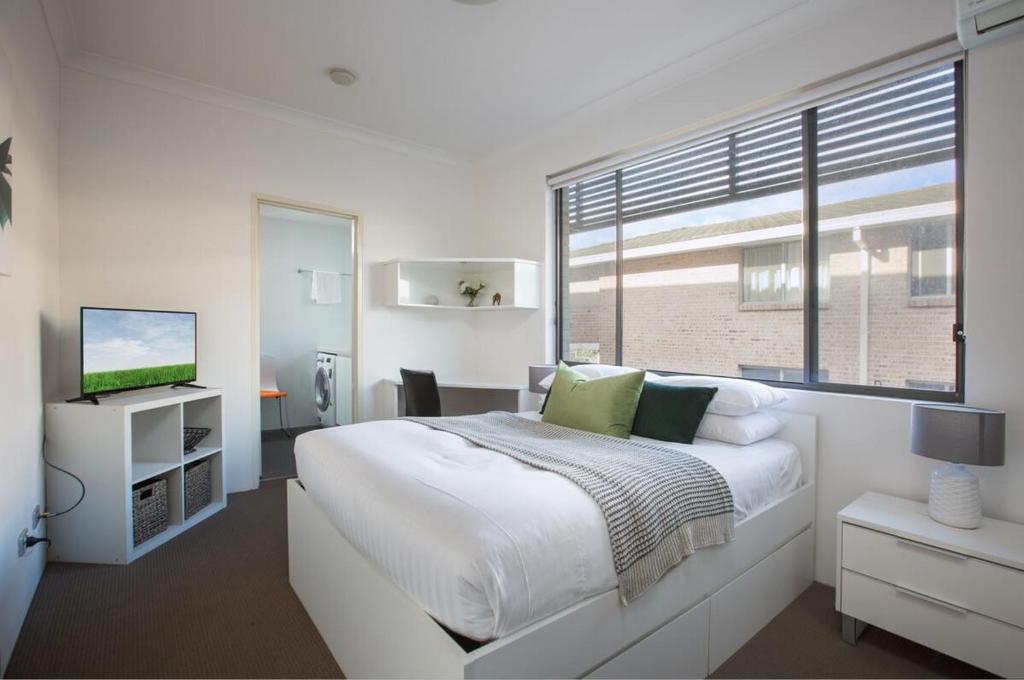 a white bedroom with a large bed and a window at Cosy and Bright Studio Next to Westmead Hospital in Sydney