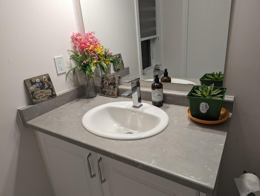 a bathroom counter with a sink and a vase of flowers at Bright Room full of love and warmth in Bowmanville