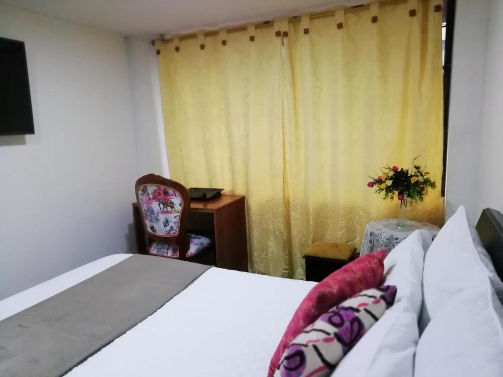 um quarto com uma cama, uma cadeira e uma janela em Habitaciones en Edificio Ginebra Manizales em La Linda