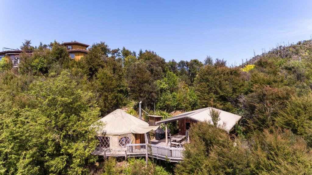 a house on the side of a hill with trees at Yurt retreat in Pangatotara