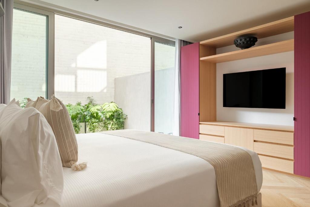 a bedroom with a white bed and a tv at Casa Cibeles by Lumina in Mexico City