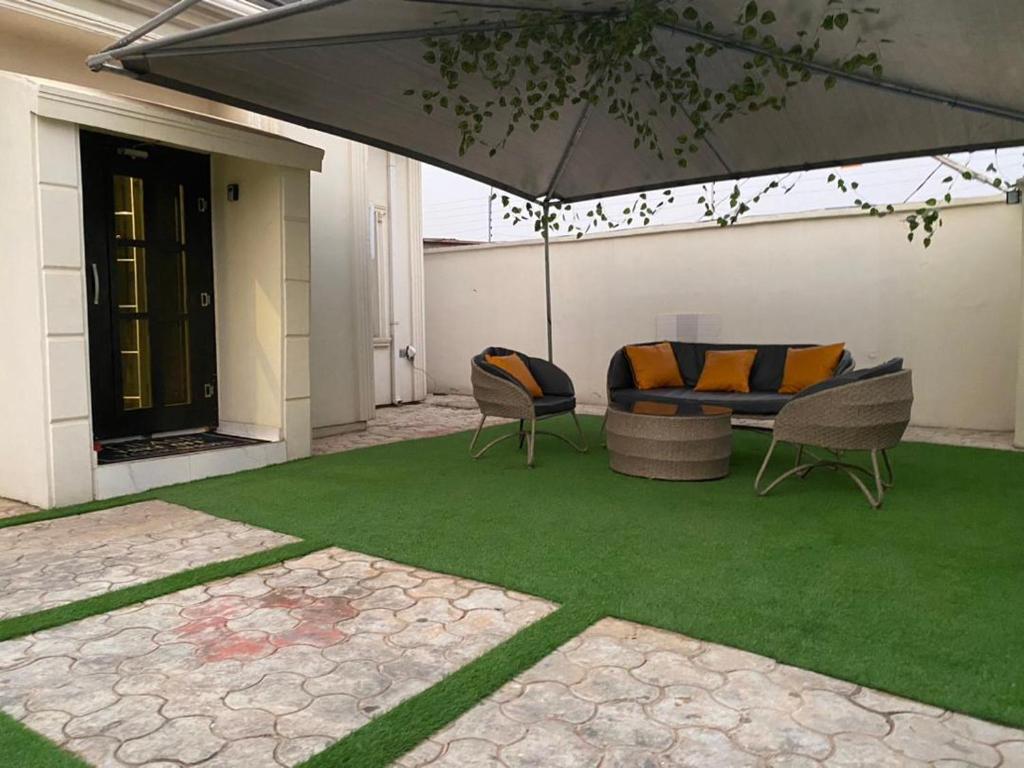 um pátio com um sofá, cadeiras e um guarda-sol em Shagari Estate Prestige 3-Bedroom Apartments. em Lagos