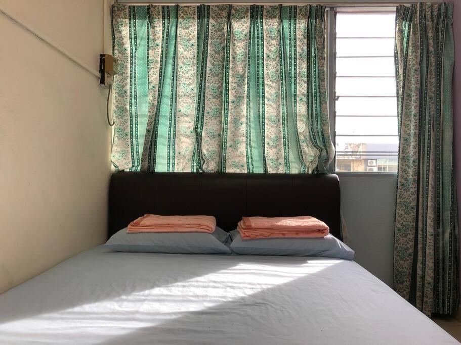 a bed with two pillows in front of a window at CLP Perai Homestay Apartment in Chai Leng park in Perai