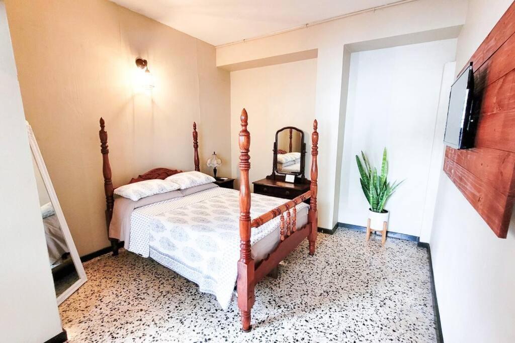 ein Schlafzimmer mit einem Bett mit einem Spiegel und einem TV in der Unterkunft Jayuya Cozy Aparment with Wi-Fi, Free Parking and AC in Jayuya