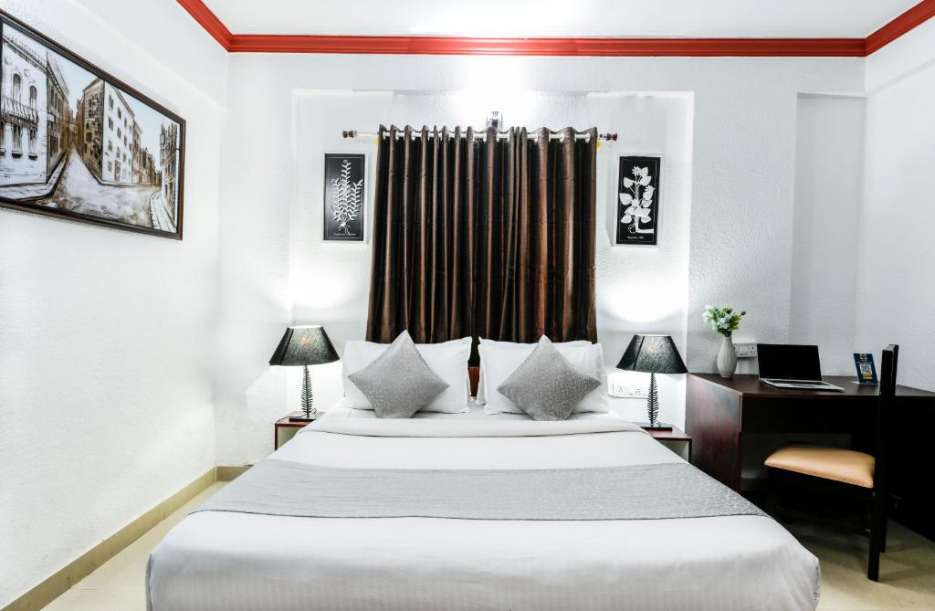 1 Schlafzimmer mit einem Bett und einem Schreibtisch sowie einem Bett der Marke sidx sidx sidx. in der Unterkunft Nevesa Inn in Bangalore