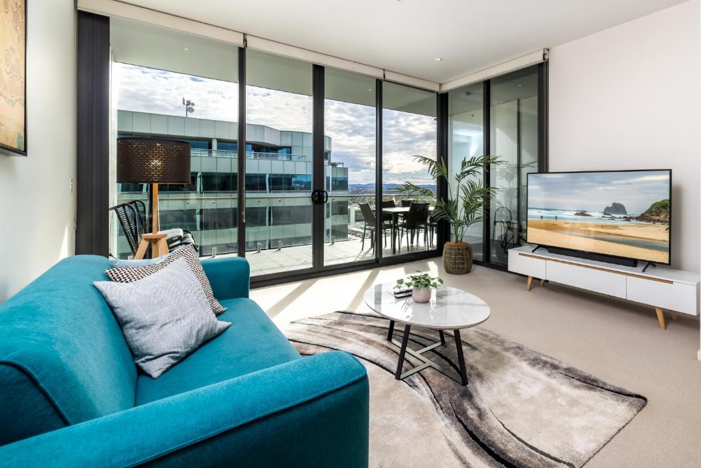 a living room with a blue couch and a tv at Spacious 1-Bed with View in Central Location in Canberra